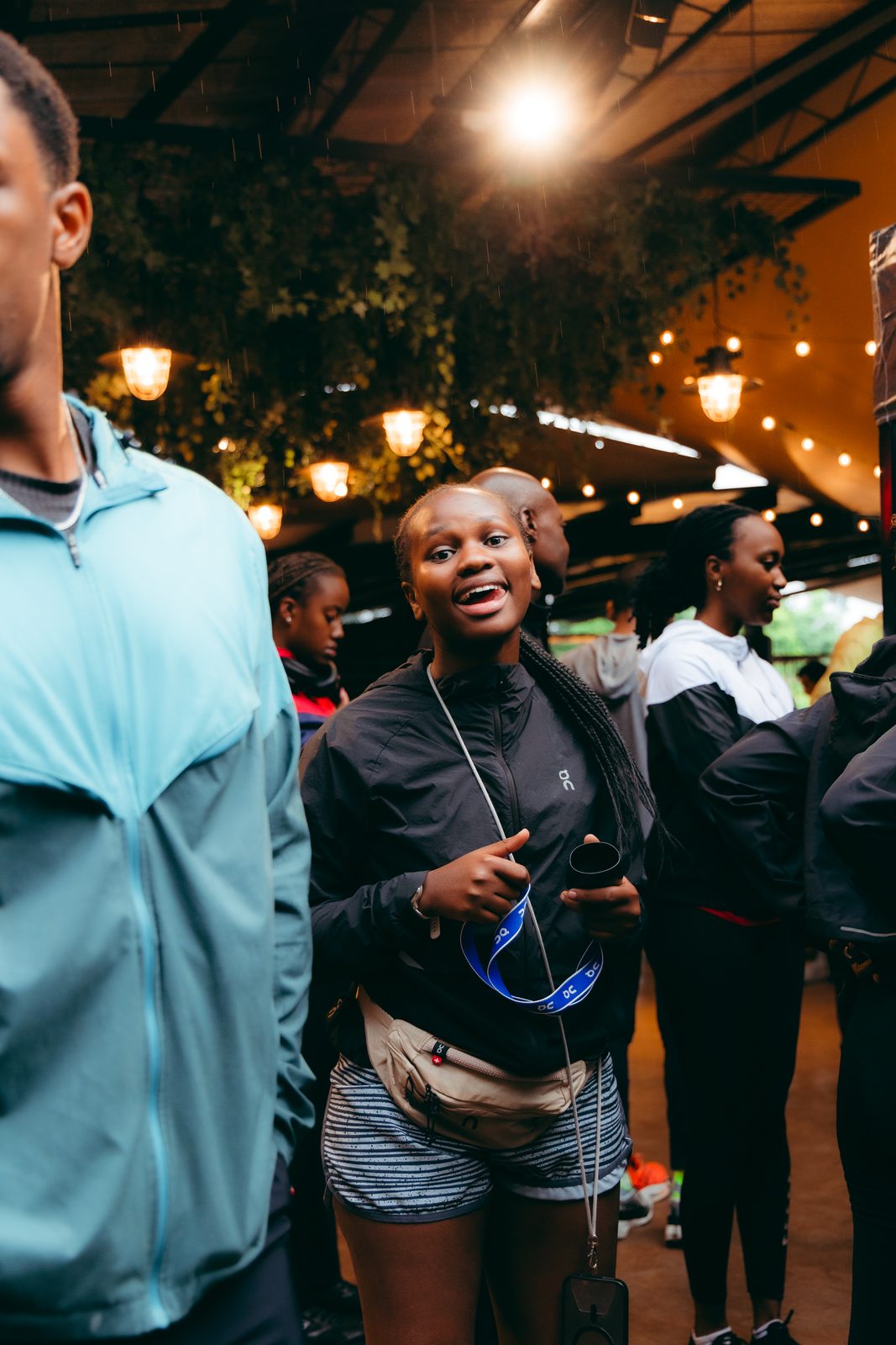 A guest in On gear smiling under string lights at an Open Lanes social